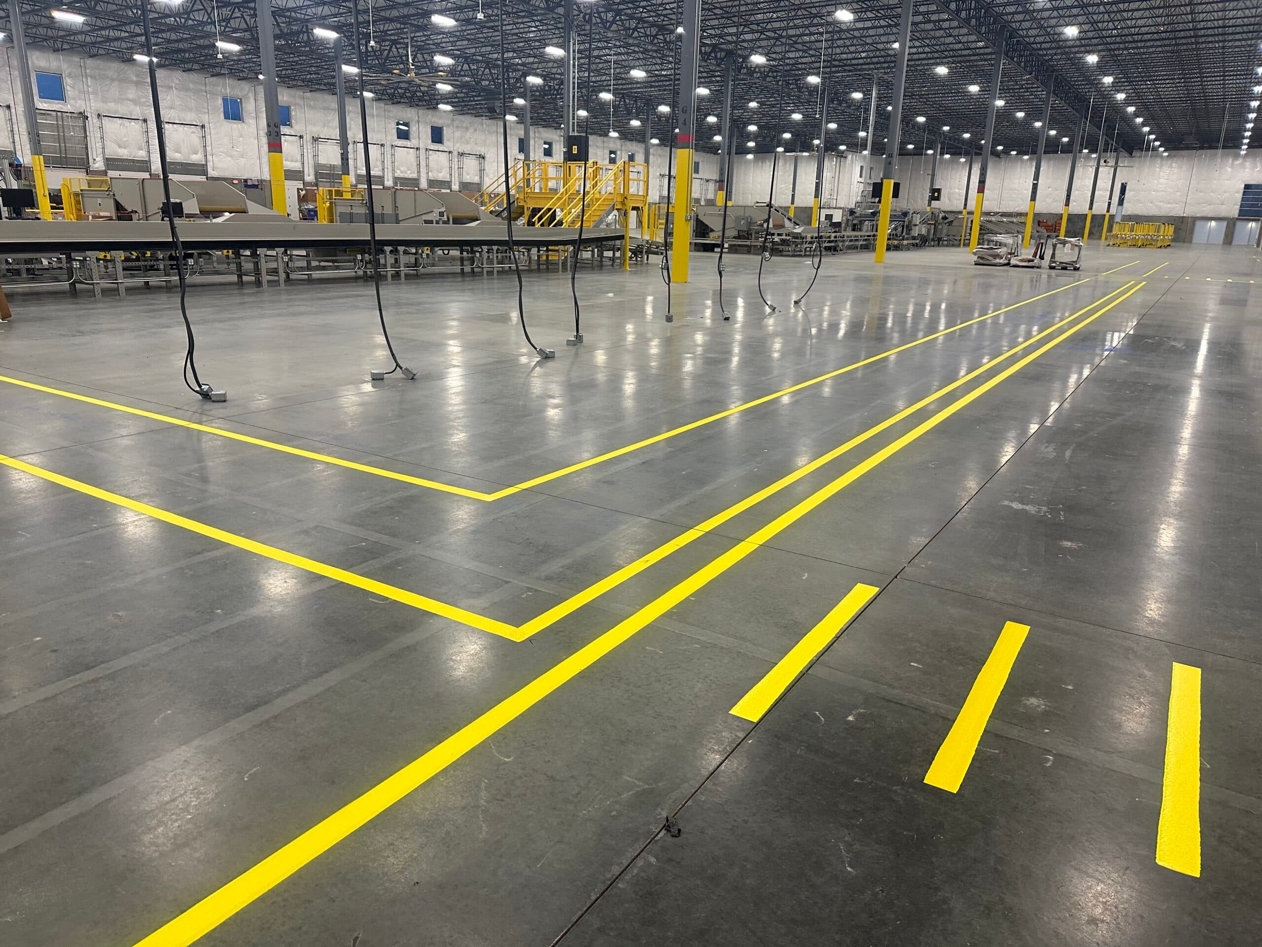 Yellow floor markings define routes and operational areas inside a large industrial facility