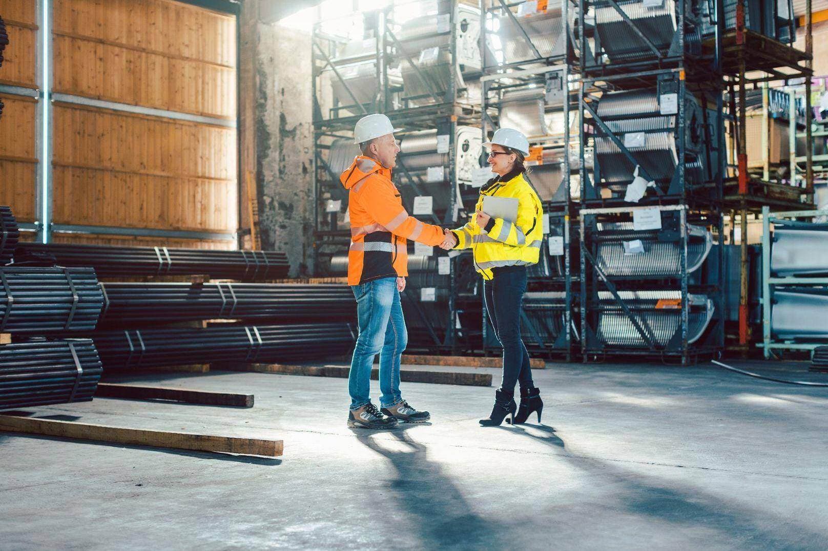 Site manager and project representative shaking hands inside a warehouse