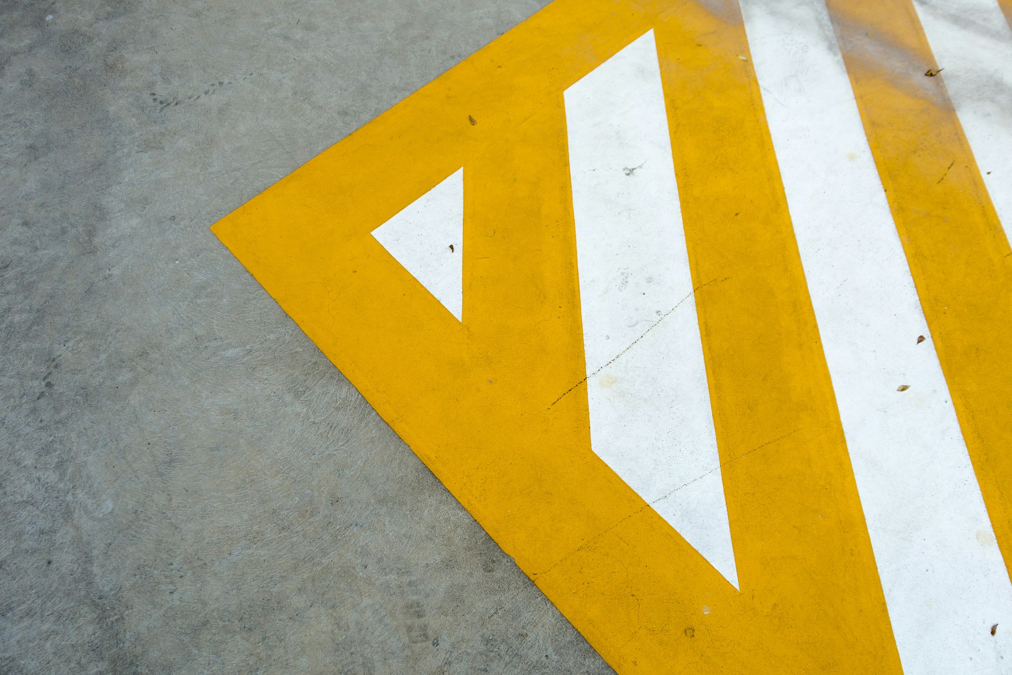 White directional marking within a yellow painted floor zone
