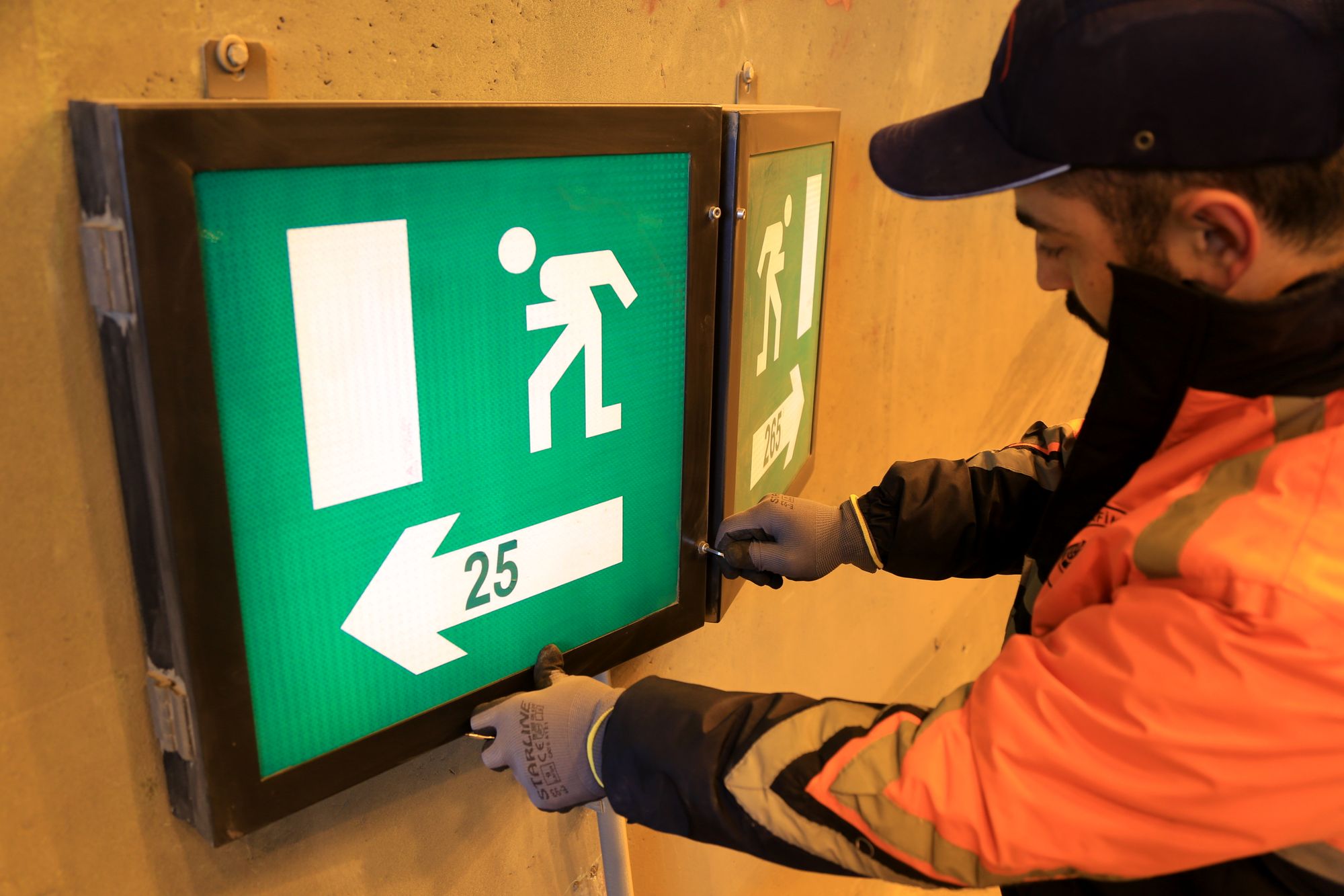 Installer securing a wall-mounted directional sign