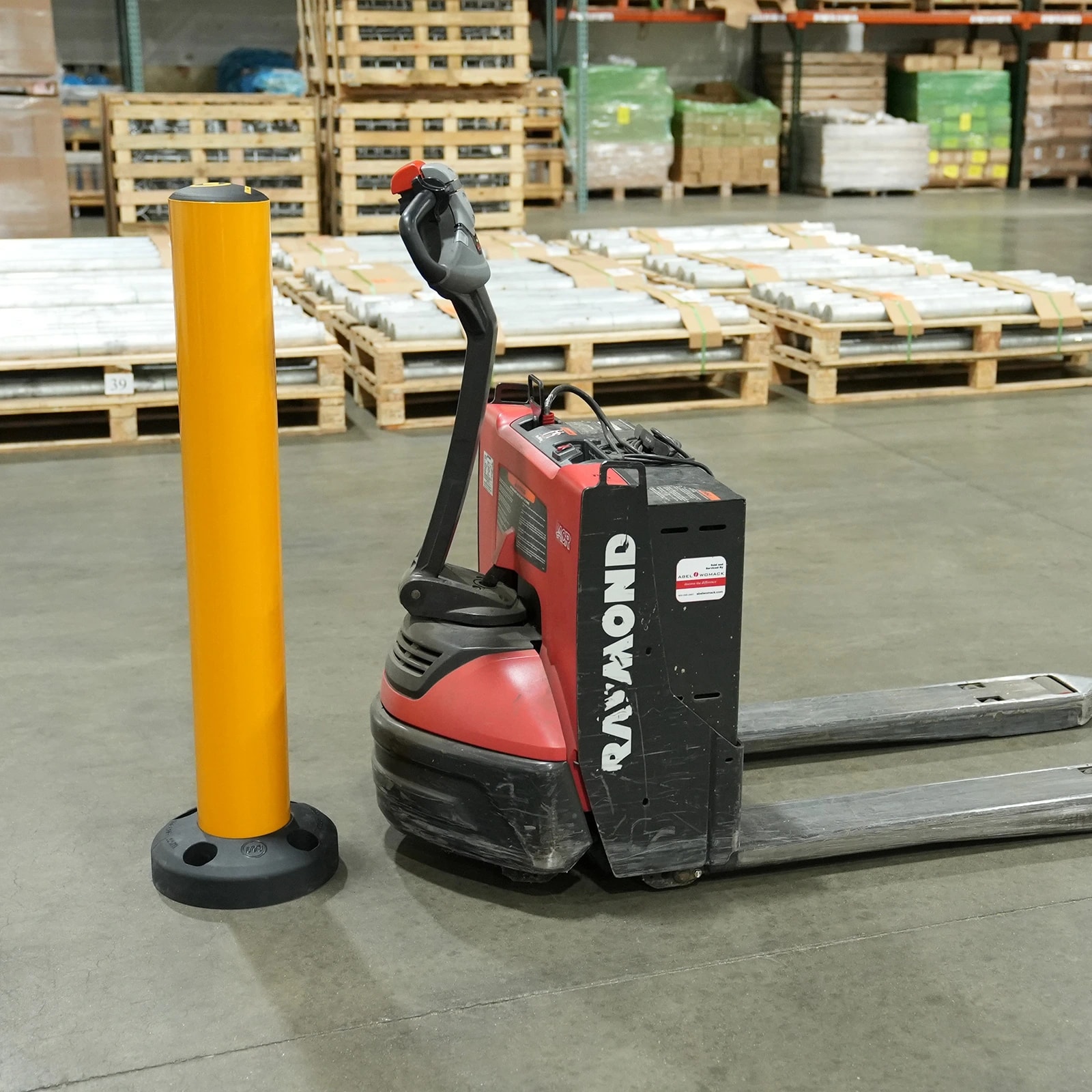 Warehouse safety bollard next to a powered pallet truck
