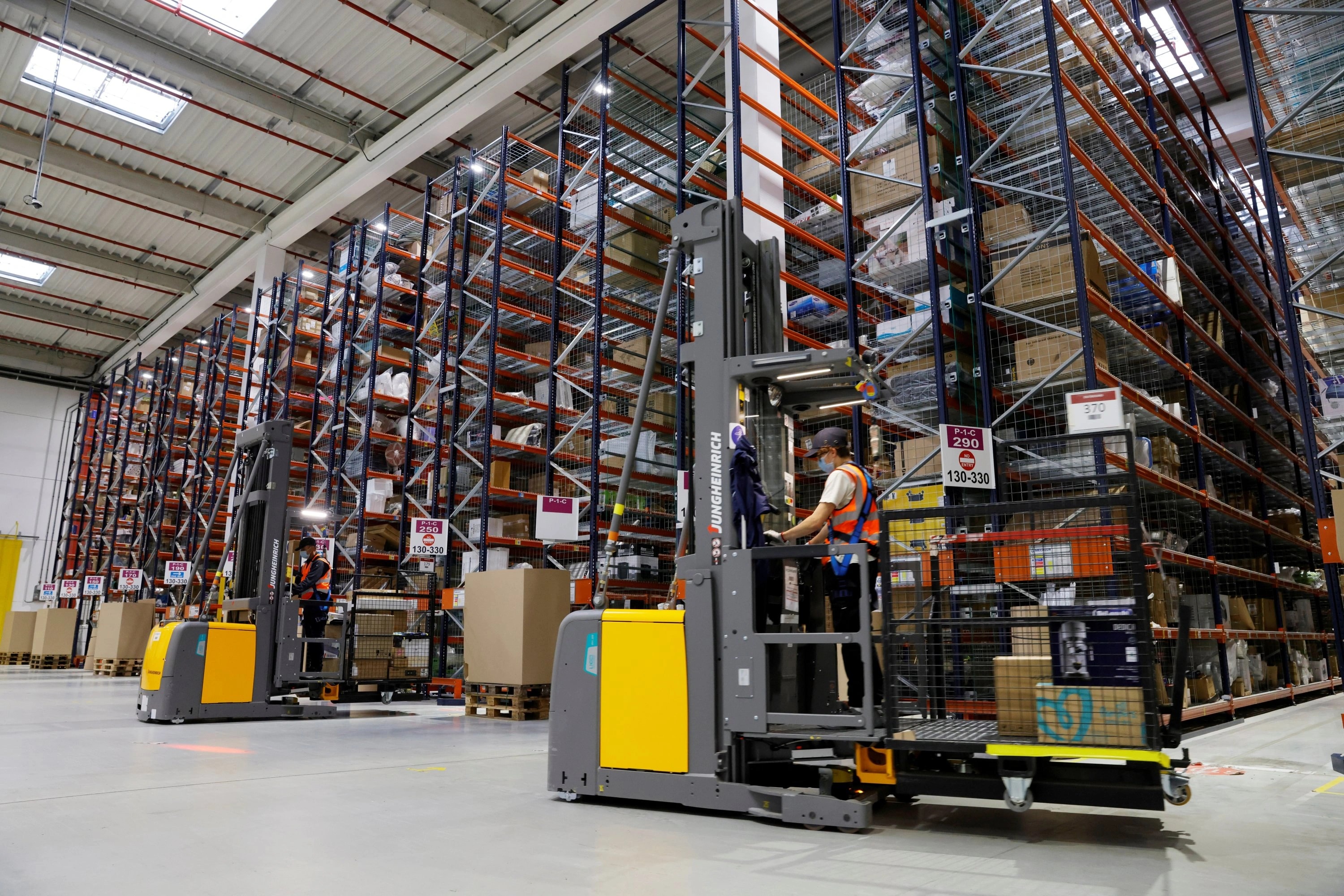 Warehouse operators using reach trucks alongside tall stocked racks