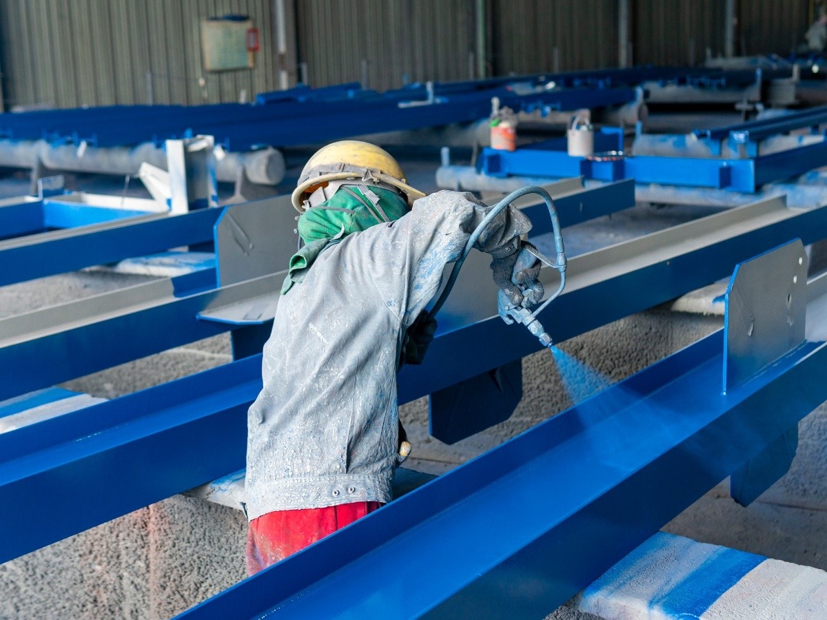 Worker applying a coating to structural steel beams