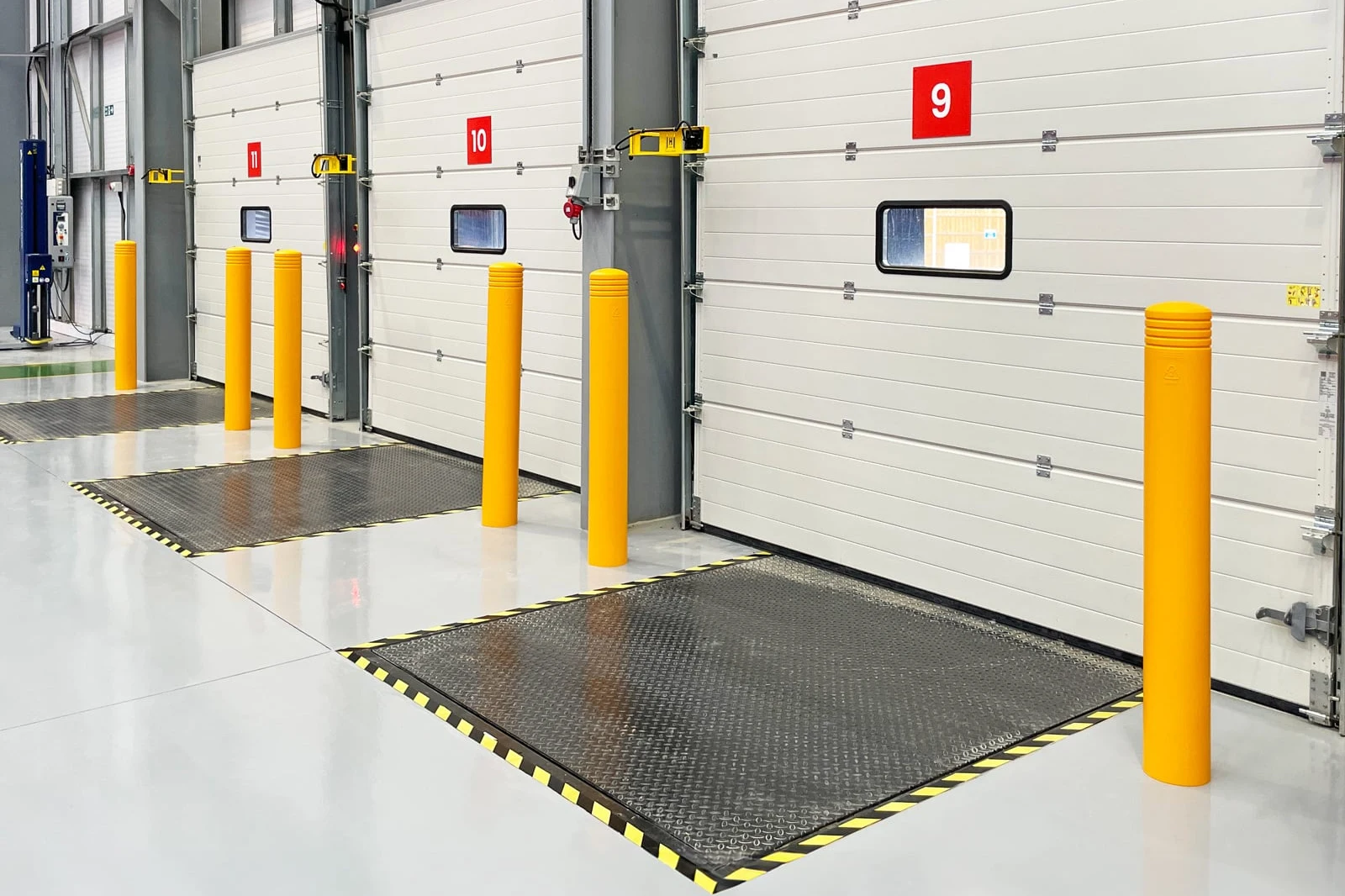 Numbered sectional loading dock doors with levelers and yellow protective bollards