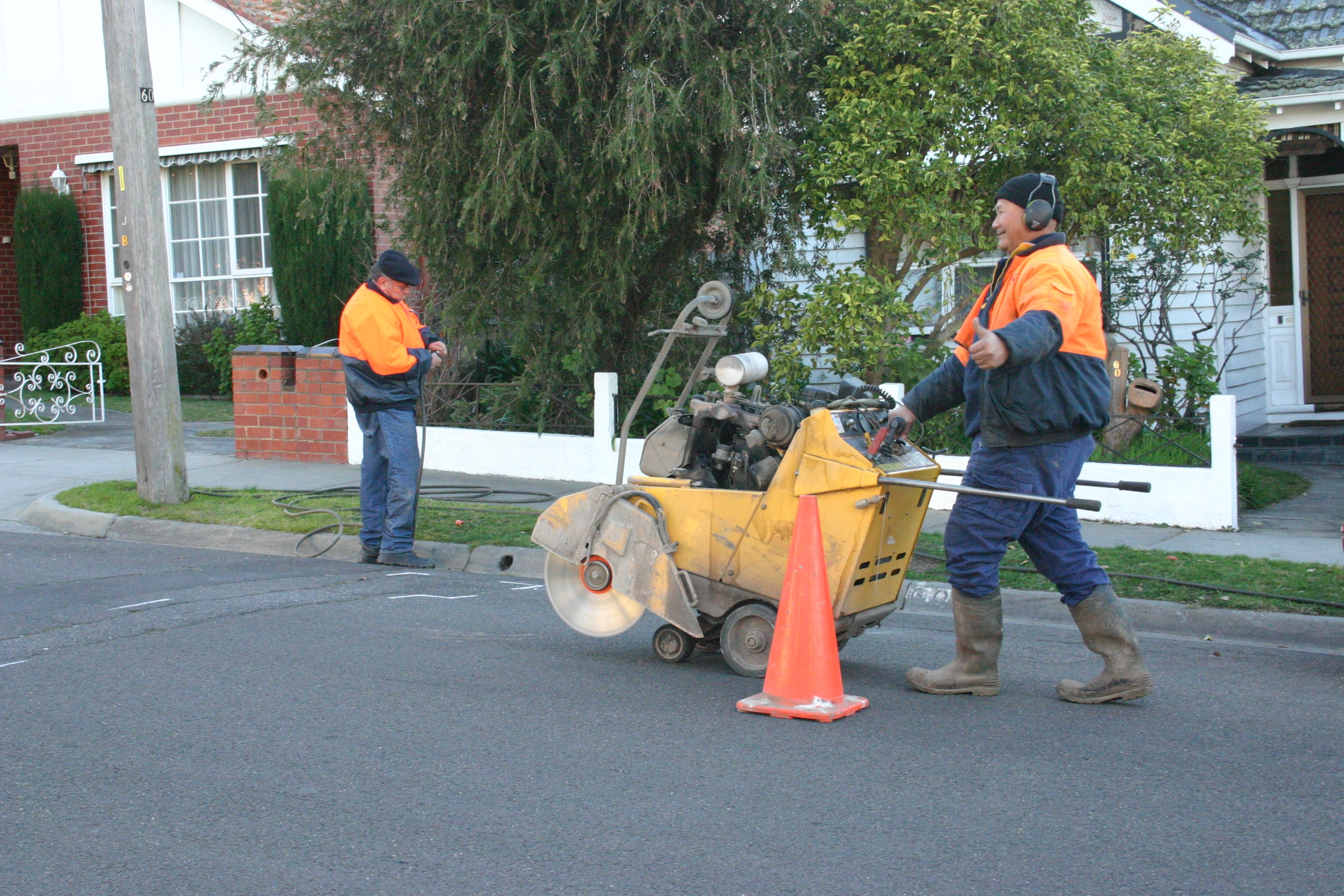 Walk-behind concrete saw being positioned for work on a paved site