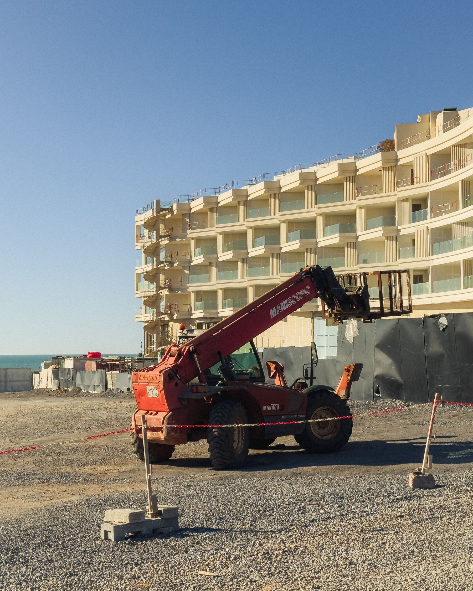 Commercial building under construction with a telehandler inside the site perimeter