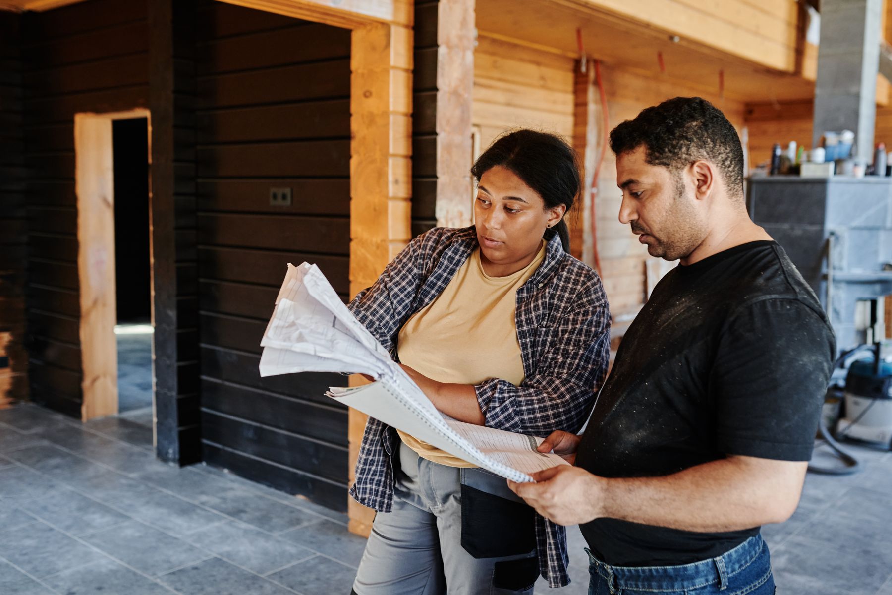 Two people reviewing construction drawings inside a building under renovation
