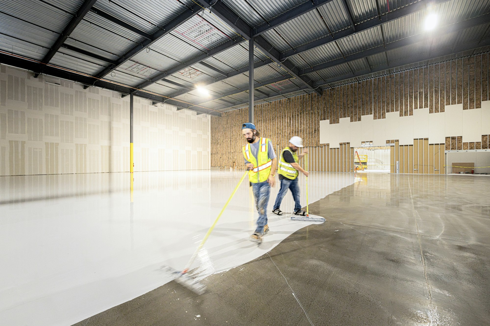 Crew applying a light-colored floor coating inside a commercial building