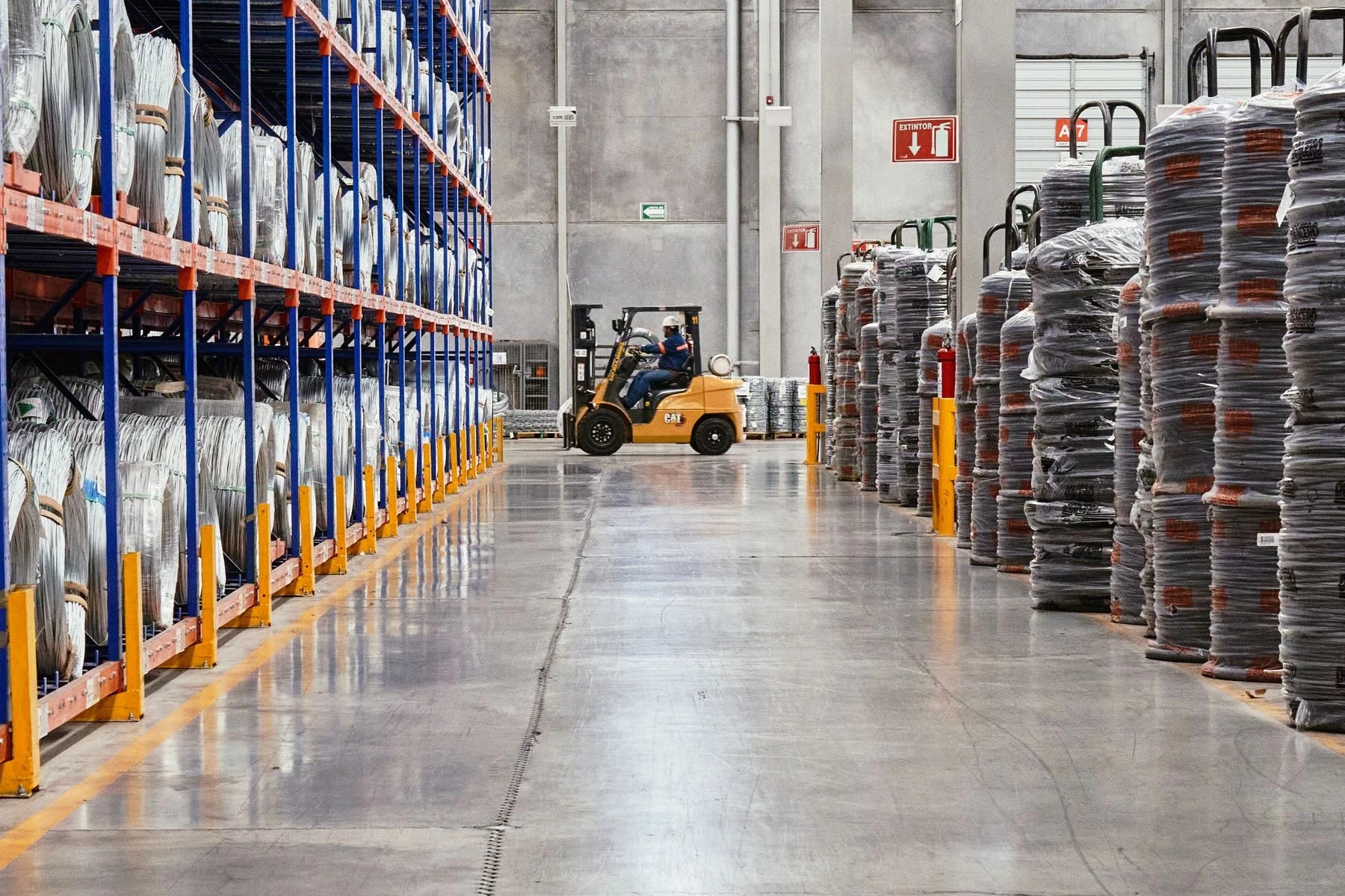 Forklift in a clear warehouse aisle beside organized material storage