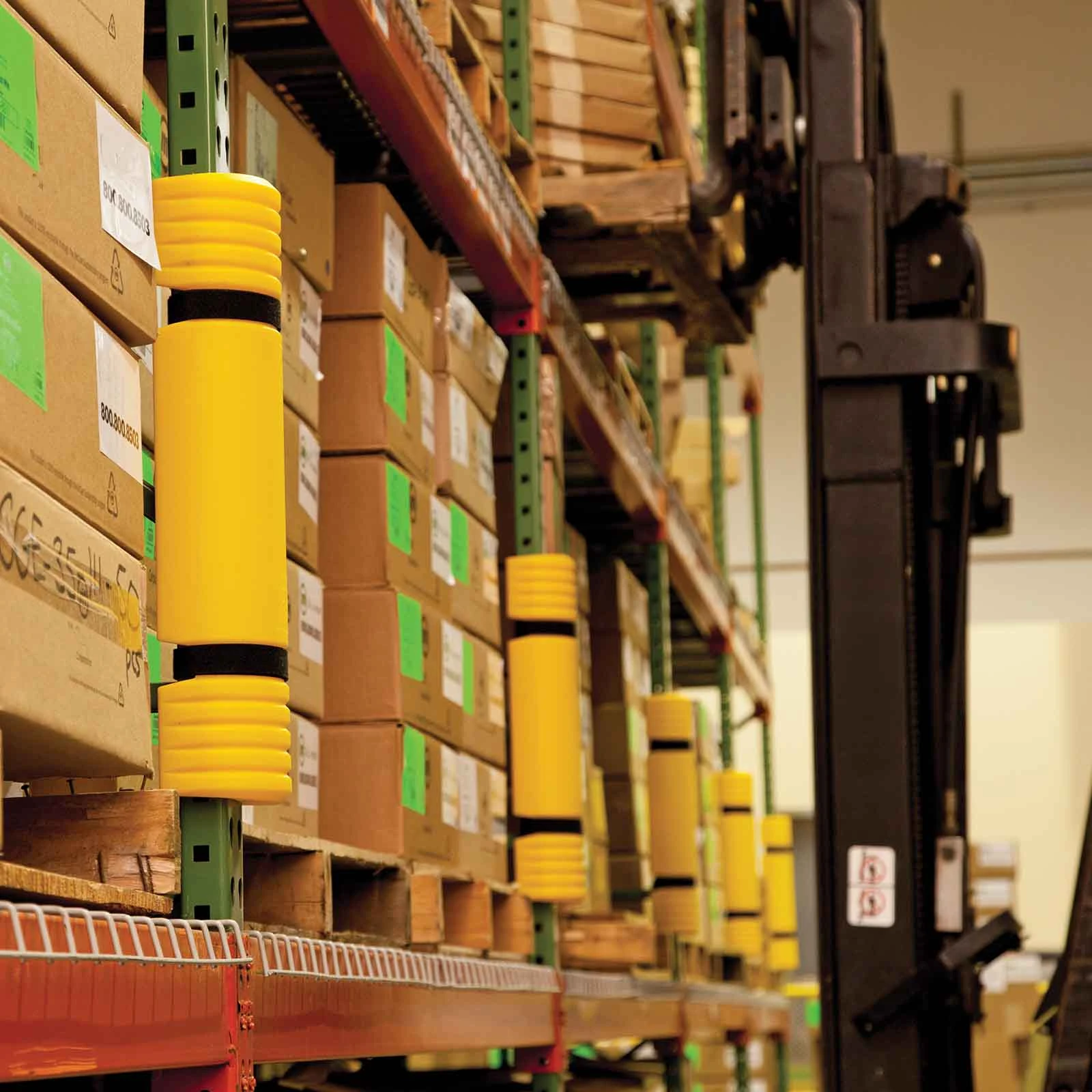 Yellow guards attached to individual rack uprights beside a forklift