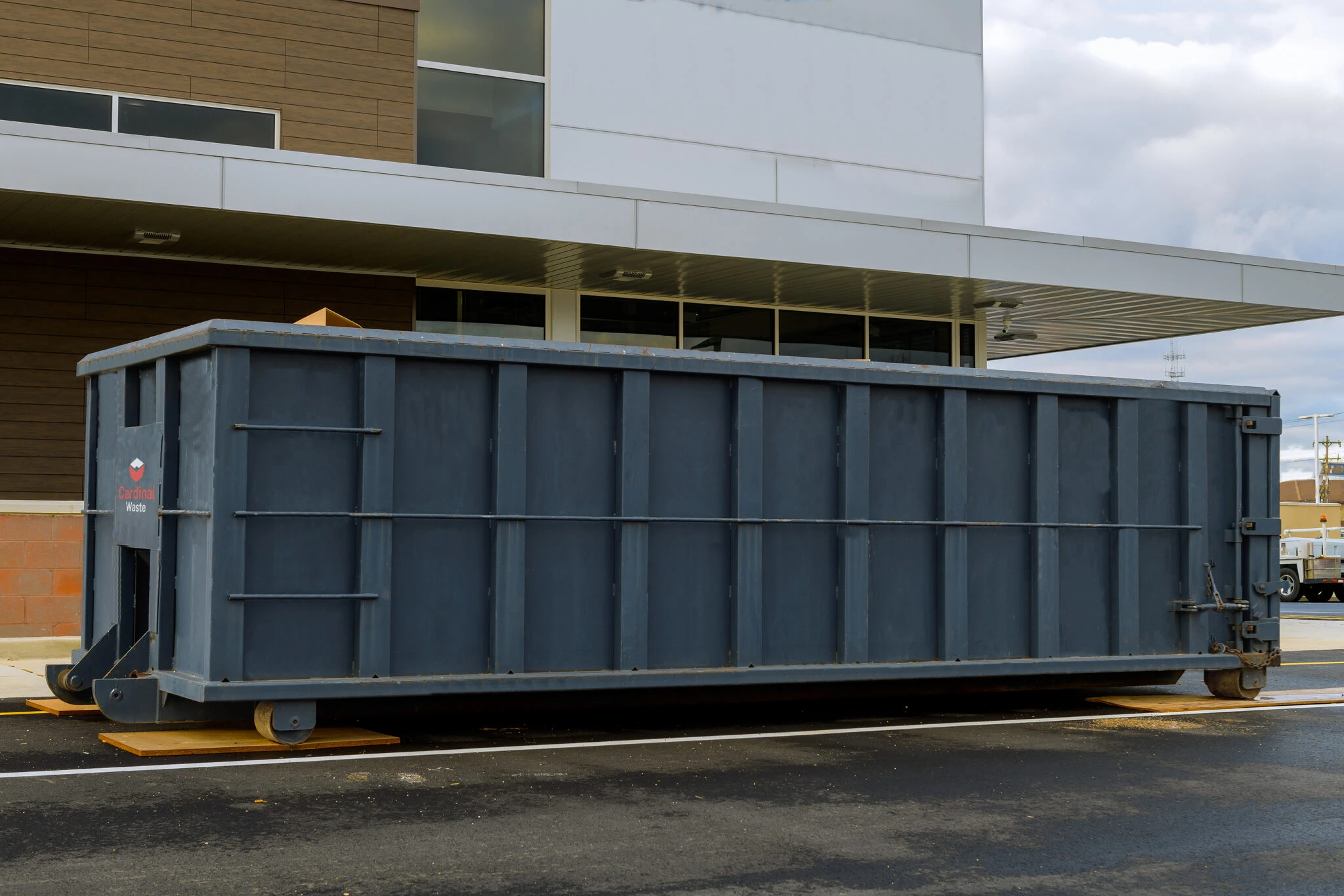 Full-size roll-off container outside a modern commercial building
