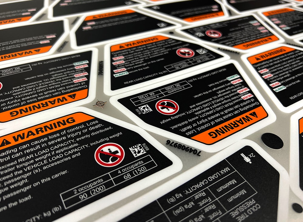 Printed warning decals and custom equipment graphics on a production sheet